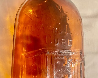 Frasco de medicamento Warner's Safe para la cura de los riñones y el hígado, de aproximadamente 9 1/2 pulgadas de alto y 3 pulgadas de ancho.