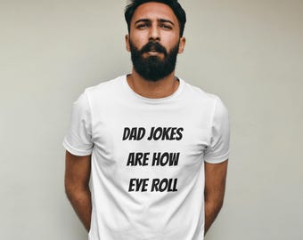 May include: White t-shirt with the text "DAD JOKES ARE HOW EYE ROLL" in black, displayed in a bold, sans-serif font. The shirt is short-sleeved and has a crew neck. The person wearing the shirt has a beard.
