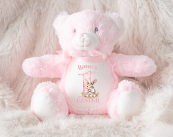 May include: Pink plush teddy bear with a white embroidered patch that says "Liane's 1st Easter" and features a bunny rabbit holding an Easter egg.