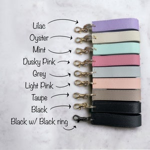 K&ouml;nnte beinhalten: Ein Set mit zehn Schl&uuml;sselanh&auml;ngern mit verschiedenen farbigen Lederriemen. Die Farben sind Lila, Perlmutt, Minze, Altrosa, Grau, Hellrosa, Taupe, Schwarz und Schwarz mit einem schwarzen Ring.