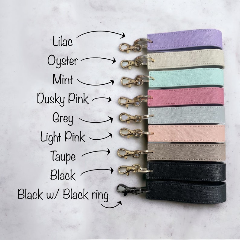 K&ouml;nnte beinhalten: Ein Set mit zehn Schl&uuml;sselanh&auml;ngern mit verschiedenen farbigen Lederriemen. Die Farben sind Lila, Perlmutt, Minze, Altrosa, Grau, Hellrosa, Taupe, Schwarz und Schwarz mit einem schwarzen Ring.