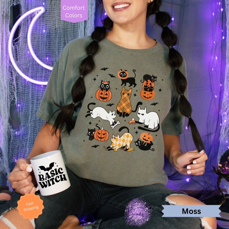 May include: A green t-shirt with a print of black cats and pumpkins. The text "Basic Witch" is on a white mug.