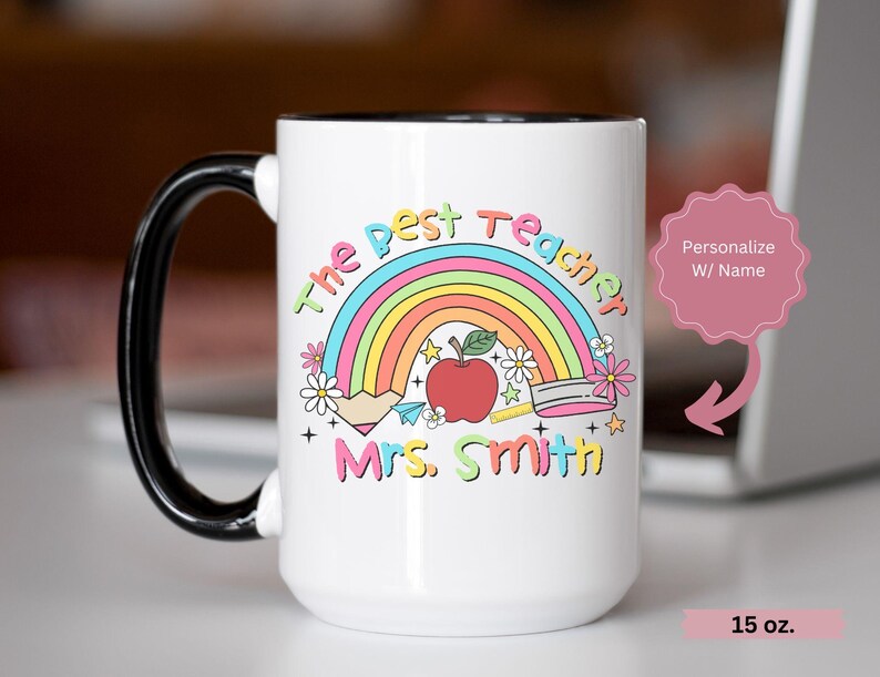 May include: White ceramic mug with a black handle. The mug has a rainbow, a red apple, and the text "The Best Teacher" and "Mrs. Smith". The mug is 15 oz.
