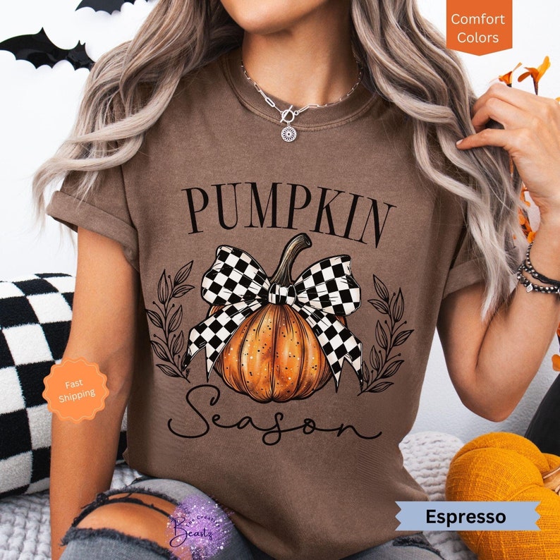 May include: A brown t-shirt with a black and white checkered bow on a pumpkin with the text "Pumpkin Season" in black.