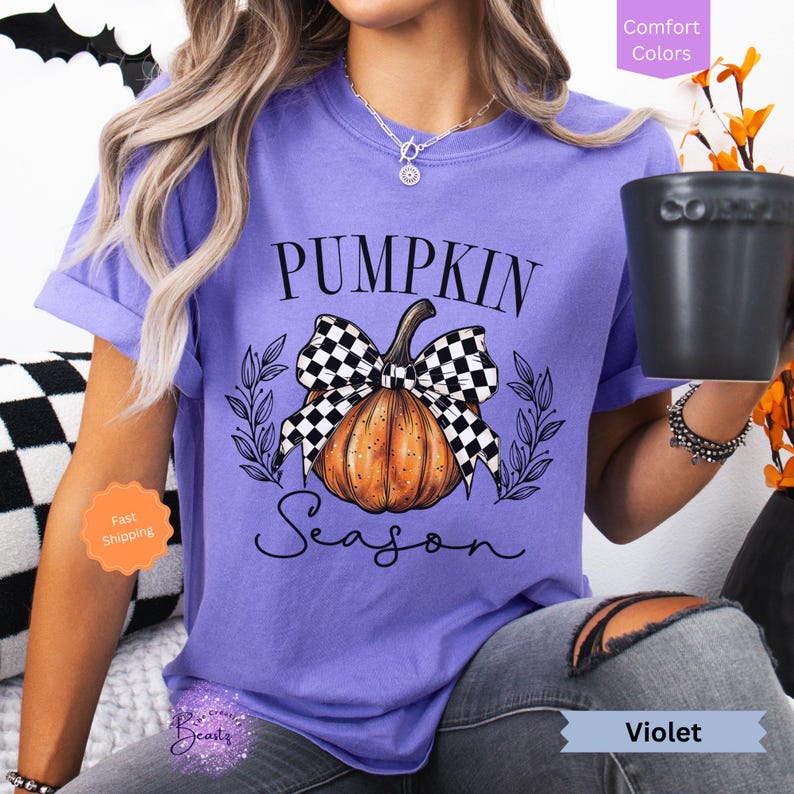 May include: A purple t-shirt with a black and white checkered bow on a pumpkin with the text "Pumpkin Season".