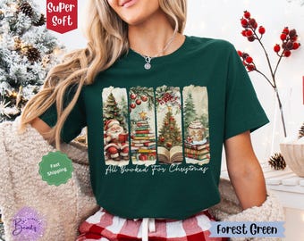 May include: Forest green t-shirt with a Christmas-themed design featuring Santa Claus, a Christmas tree, and a stack of books. The text "All Booked For Christmas" is printed on the shirt.