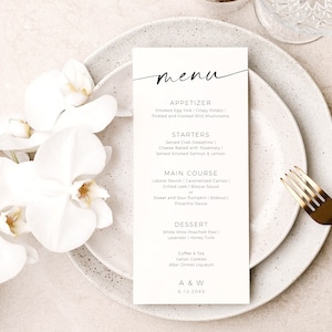 May include: A white menu card with a black handwritten 'menu' title. The menu lists appetizers, starters, main course, dessert, coffee and tea, Italian cookies, after dinner liqueurs, and A & W. The date 6.10.20XX is printed at the bottom of the card. The card is on a white plate with a gold fork on the right side of the plate. A white orchid is in the background.