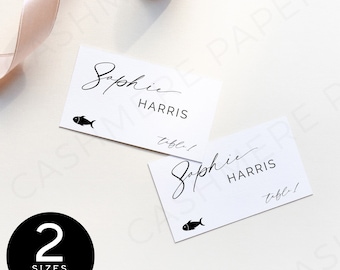 May include: Two white place cards with black text and a small fish icon. The text reads "Sophie Harris" and "table!"
