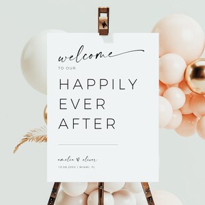 Pode incluir: Um letreiro de boas-vindas branco com texto preto que diz "Bem-vindos ao nosso felizes para sempre Amelia & Oliver 10.08.20XX | Miami, FL". O letreiro est&aacute; em um cavalete de madeira com um grupo de bal&otilde;es p&ecirc;ssego e ouro atr&aacute;s.