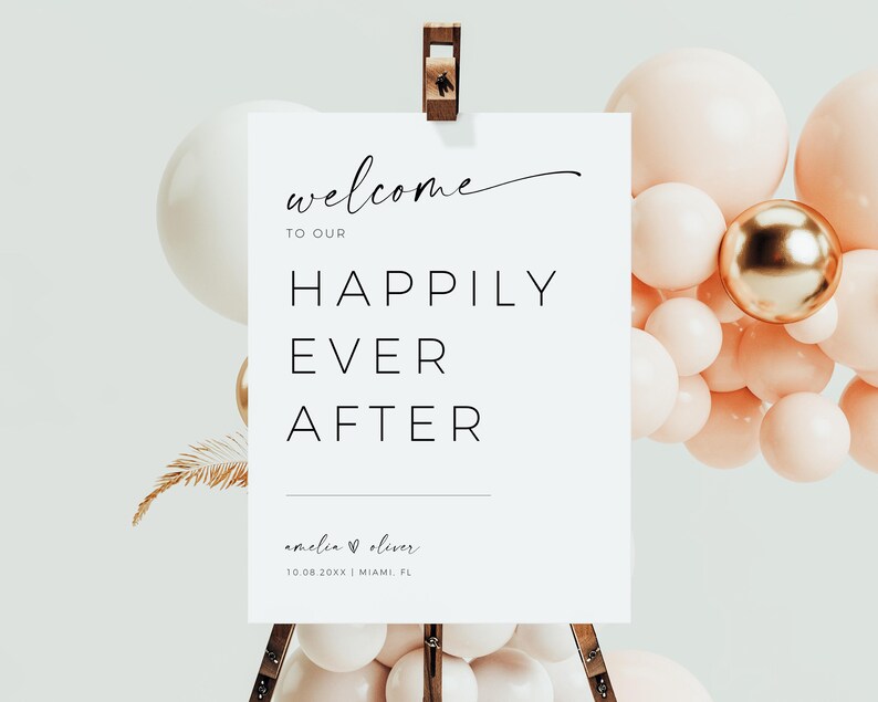 May include: White welcome sign with black text that reads "Welcome to our Happily Ever After Amelia & Oliver 10.08.20XX | Miami, FL". The sign is on a wooden easel with a cluster of peach and gold balloons behind it.
