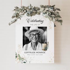 May include: A memorial print featuring a black and white photo of a woman wearing a hat and glasses. The text "Celebrating the Life of Gertrude Monroe" is above the photo, with dates below. The print is decorated with floral accents.