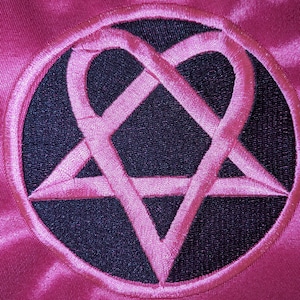 May include: A pink fabric patch with a black pentagram embroidered in white. The pentagram has a heart shape in the center.