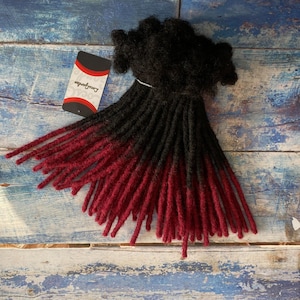 May include: Black and burgundy ombre synthetic dreadlocks. The dreadlocks are tied together with a black string.