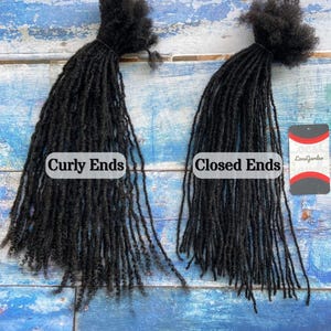 May include: Two bundles of black dreadlocks, one with curly ends and the other with closed ends, are displayed against a blue and white wooden background. The text "Curly Ends" and "Closed Ends" are visible. A tag with the text "LocsGarden" is also visible.