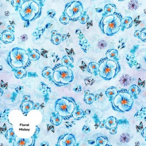Puede incluir: Un patr&oacute;n repetido de flores de acuarela azul claro con centros naranjas y mariposas sobre un fondo blanco. El dise&ntilde;o incluye el texto "Floral Mickey" en un c&iacute;rculo blanco.