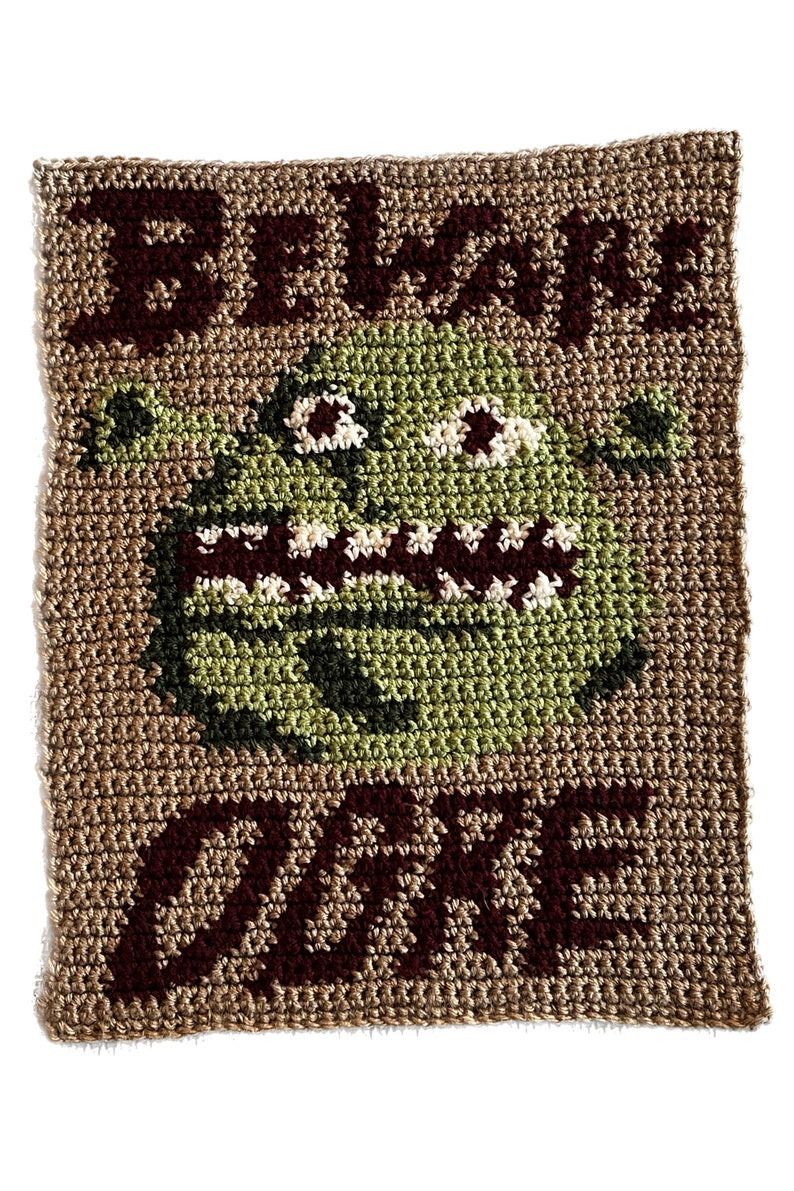 May include: Crocheted wall hanging with the text "Beware Ogre" in brown yarn. A green ogre face is in the center of the hanging.