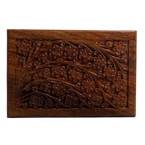 Puede incluir: Una caja de madera con un dise&ntilde;o floral tallado. La caja est&aacute; hecha de madera marr&oacute;n oscura y tiene una forma rectangular.