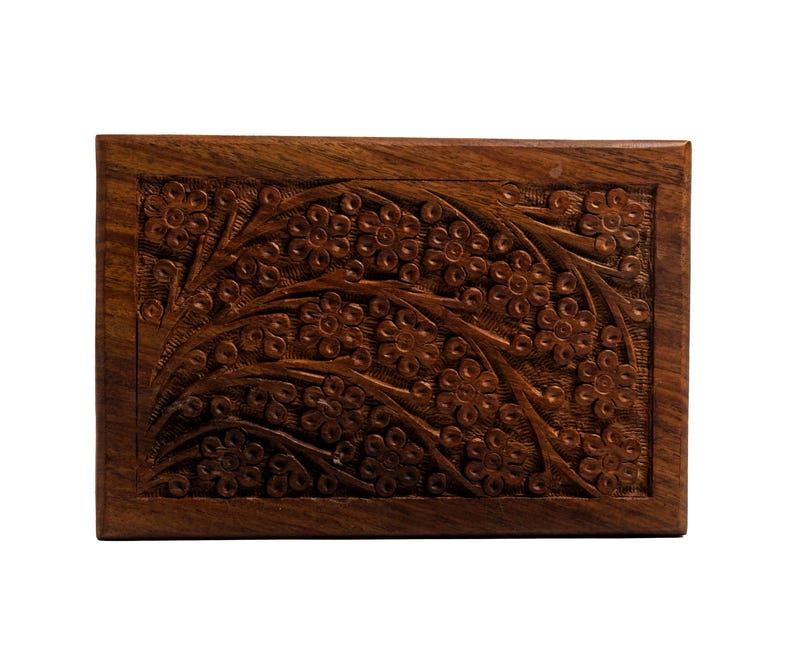 Puede incluir: Una caja de madera con un dise&ntilde;o floral tallado. La caja est&aacute; hecha de madera marr&oacute;n oscura y tiene una forma rectangular.