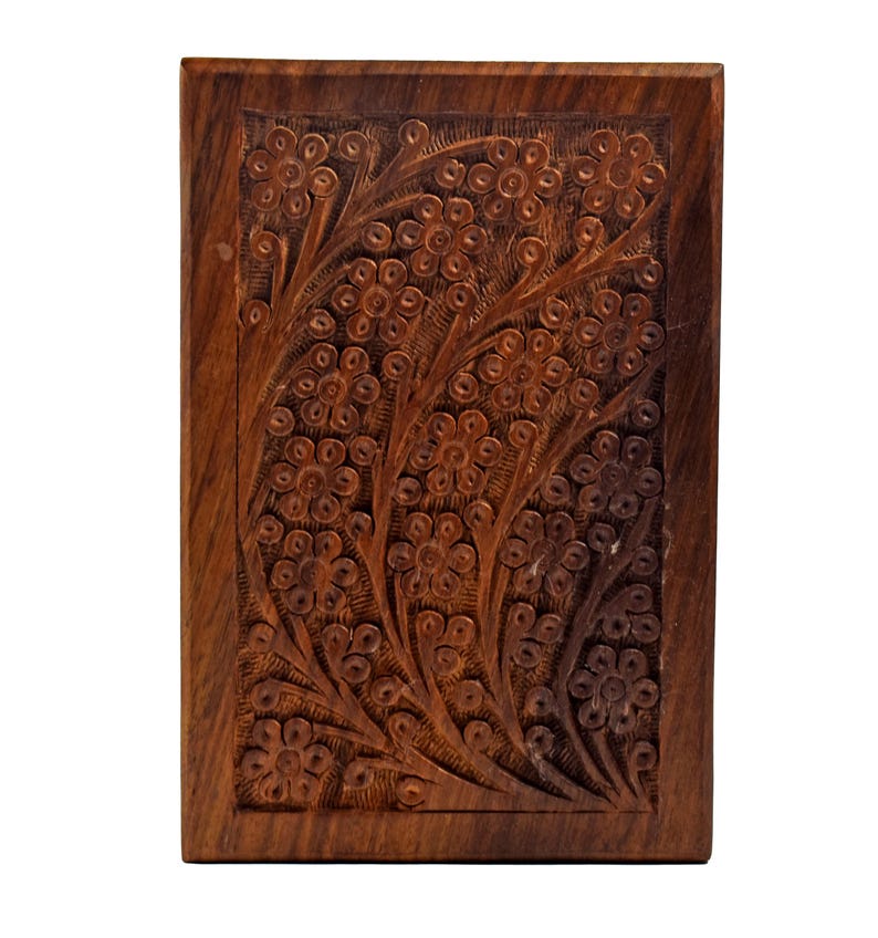 Puede incluir: Una caja de madera con un dise&ntilde;o floral tallado. La caja est&aacute; hecha de madera marr&oacute;n oscura y tiene una forma rectangular.