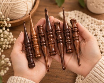 May include: A set of seven dark brown wooden crochet hooks with smooth, polished surfaces and ergonomic handles. Each hook features a distinct turned wood design with varying thicknesses and tapered points, showcasing natural wood grain patterns.
