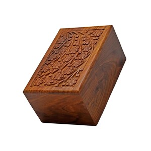 Puede incluir: Una caja de madera con un dise&ntilde;o floral tallado en la parte superior. La caja est&aacute; hecha de madera marr&oacute;n oscura y tiene una forma rectangular.