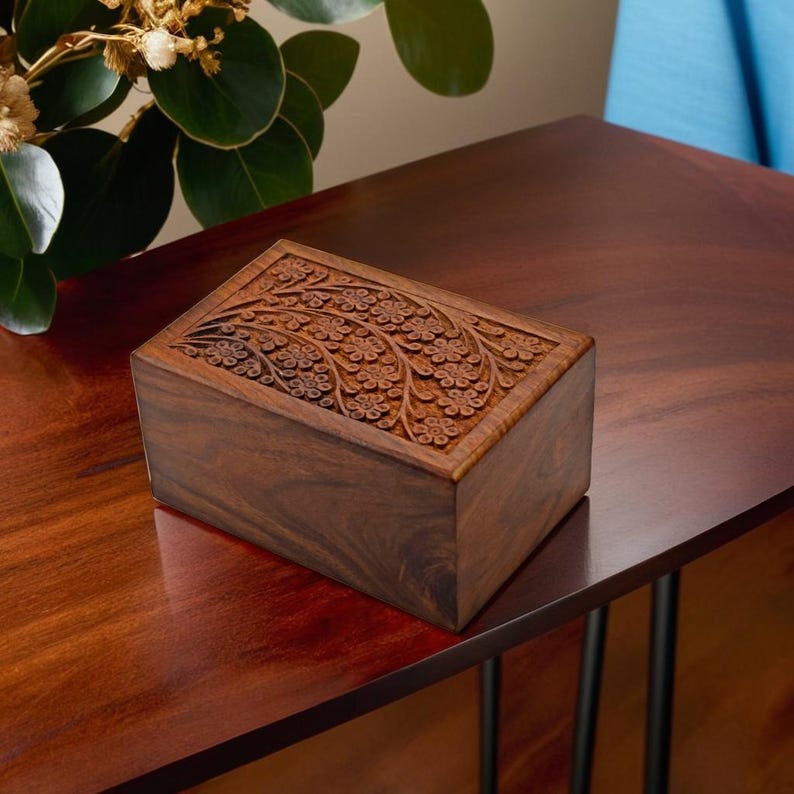 Puede incluir: Una caja de madera con un dise&ntilde;o floral tallado. La caja est&aacute; hecha de madera oscura y tiene una forma rectangular.