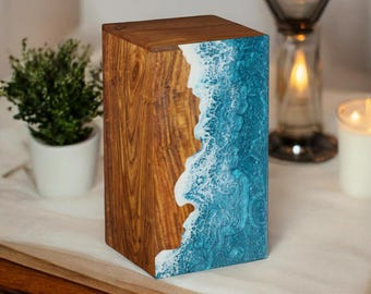 May include: A wooden box with a blue and white resin inlay that resembles ocean waves. The box is made of dark wood with a natural grain pattern.