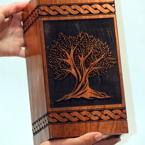 May include: A wooden box with a carved tree of life design. The box is made of dark wood and has a Celtic knot border.