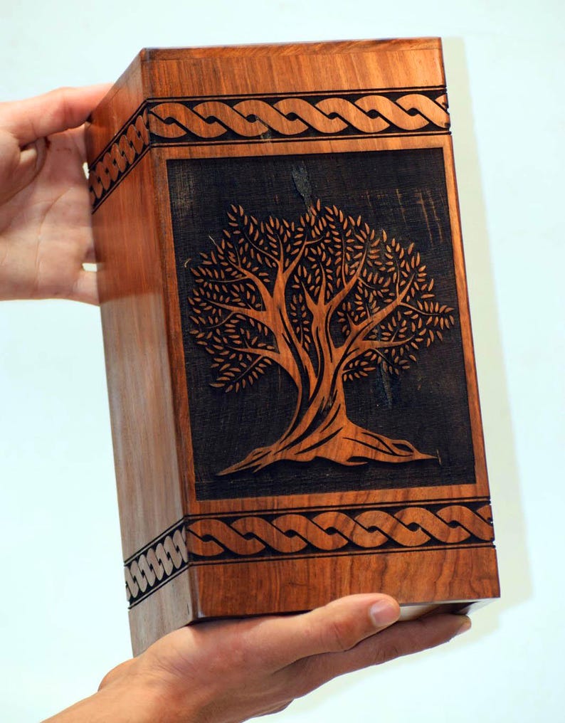 May include: A wooden box with a carved tree of life design. The box is made of dark wood and has a Celtic knot border.