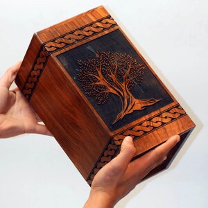 May include: A wooden box with a Celtic knot design around the edges and a carved tree of life design on the front.