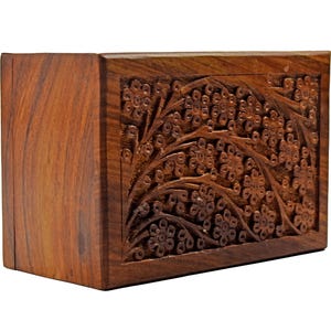Puede incluir: Una peque&ntilde;a caja de madera con un dise&ntilde;o floral tallado. La caja est&aacute; hecha de madera marr&oacute;n oscura y tiene una forma rectangular.