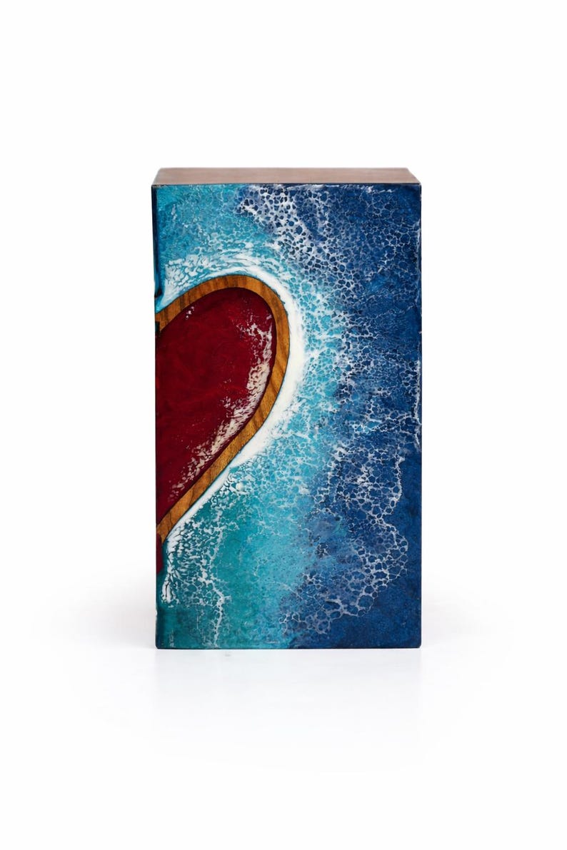 May include: A rectangular wooden box with a heart-shaped design. The heart is filled with red resin and framed by a wooden border. The background features a blue and white wave pattern, creating a coastal theme.