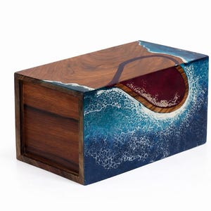 May include: A rectangular wooden box with a unique design. The top and sides feature a wood grain pattern, while the front and sides are adorned with a blue and white wave design. The interior is a deep red color.