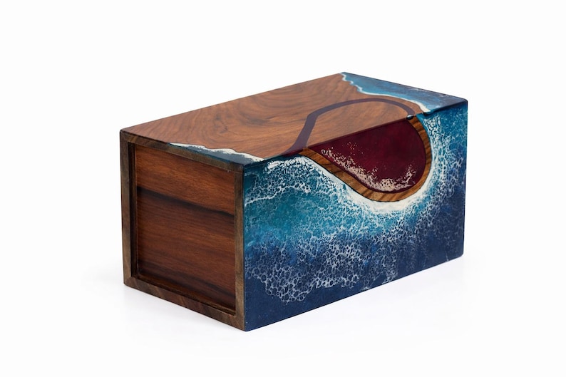 May include: A rectangular wooden box with a unique design. The top and sides feature a wood grain pattern, while the front and sides are adorned with a blue and white wave design. The interior is a deep red color.