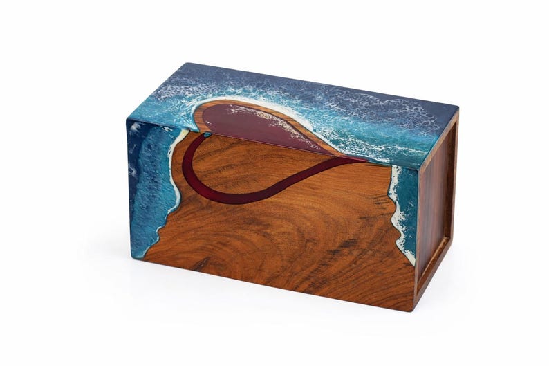 May include: A rectangular wooden box with a heart-shaped design. The top and sides feature a blue and white wave pattern, while the front displays a heart-shaped design in red. The box is made of wood with a natural grain.