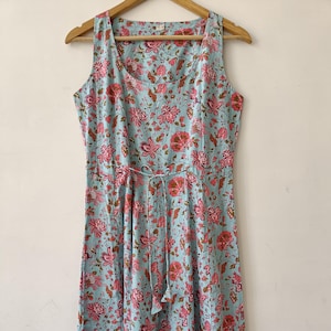 Puede incluir: Un vestido maxi azul claro con estampado floral. El vestido tiene un escote redondo, es sin mangas y tiene un lazo en la cintura.