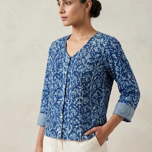 Op de afbeelding: Een blauw overhemd met patroon en driekwartmouwen. Het overhemd heeft een V-hals en een bloemenpatroon in blauwtinten. De manchetten hebben een streepjespatroon. Het overhemd wordt gecombineerd met een off-white broek.