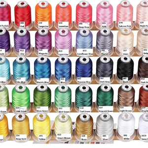 May include: A collection of colorful thread spools arranged on wooden shelves. The spools are labeled with color names and numbers, including shades of red, pink, blue, green, and brown. The threads are tightly wound, ready for sewing or embroidery projects.