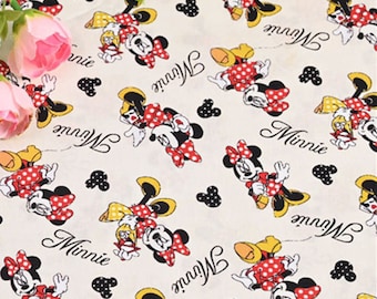 Puede incluir: Tela blanca con un patrón repetido de Minnie Mouse en rojo, amarillo y negro. La tela tiene la palabra "Minnie" escrita en letra negra.
