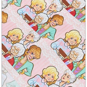 May include: A pink and white patterned fabric with a repeating design of four cartoon women. The women are wearing colorful outfits and have different hairstyles. The fabric is perfect for crafting projects, such as making bags, pillows, or quilts.