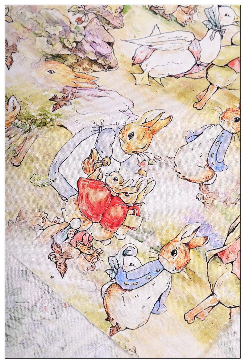 May include: A white fabric with a repeating pattern of watercolor illustrations of bunnies and a duck. The bunnies are wearing blue and white clothing and carrying other bunnies. The duck is wearing a pink and white dress.
