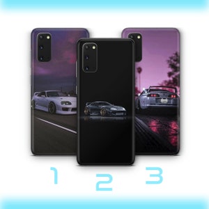 May include: Three phone cases with different designs featuring a white sports car. The first case has a purple and pink gradient background with a white sports car driving on a road. The second case has a black background with a white sports car driving on a road. The third case has a purple and pink gradient background with a white sports car driving on a road.