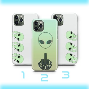 Peut inclure: Trois coques de téléphone iPhone avec des designs différents. La première coque a un fond blanc avec quatre extraterrestres verts avec un doigt levé. La deuxième coque a un fond dégradé vert à jaune avec une tête d'extraterrestre verte et un majeur noir avec les mots "F**K YOU" écrits dessus. La troisième coque est la même que la première.