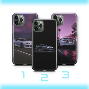 Peut inclure: Trois étuis de téléphone différents avec un fond noir, blanc et violet foncé. Chaque étui présente une image différente d'une voiture de sport blanche avec un intérieur noir. La voiture du premier étui roule sur une route avec un ciel violet en arrière-plan. La voiture du deuxième étui roule sur une surface noire avec un ciel noir en arrière-plan. La voiture du troisième étui roule sur une route avec un ciel violet en arrière-plan. La voiture du troisième étui a une plaque d'immatriculation qui indique "F-R35C".