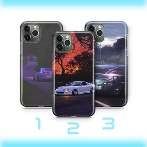 Puede incluir: Tres fundas de teléfono diferentes con un tema de coche. La primera funda es negra con un coche morado en una carretera. La segunda funda tiene un fondo de puesta de sol con un coche blanco en una carretera. La tercera funda tiene un fondo oscuro con un coche blanco en una carretera.