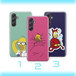 May include: Three smartphone cases labelled 1, 2, and 3. Case 1 is sage green with Homer Simpson wearing glasses. Case 2 is pink with Homer Simpson wrapped in a blanket. Case 3 is dark blue with a graphic of Homer Simpson dressed as a red devil.