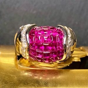 May include: A ring with a large, round, pink ruby surrounded by smaller diamonds. The ruby is set in a gold band.