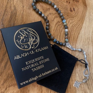 Puede incluir: Cuentas de oraci&oacute;n Ablagh-Ul-Kalaam Tasbih con una caja negra y una peque&ntilde;a bolsa negra. Las cuentas son una mezcla de piedras grises, azules y marrones. La caja tiene letras doradas y la direcci&oacute;n del sitio web www.ablagh-ul-kalaam.co.uk.