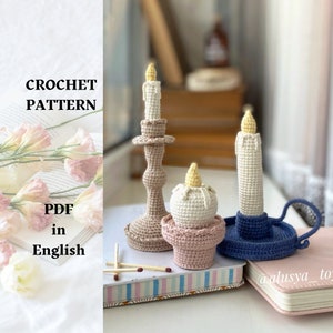 May include: Crochet pattern PDF in English for three crocheted candles. One candle is in a brown candlestick, one is in a blue candlestick, and one is on a pink base. The candles are white with yellow flames.