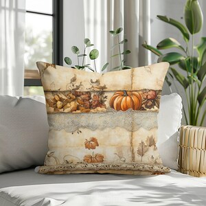 May include: A square throw cushion featuring a vintage-style parchment background with a printed design of an orange pumpkin, brown autumn leaves, and delicate cream-coloured lace trim accents layered horizontally across the fabric surface.